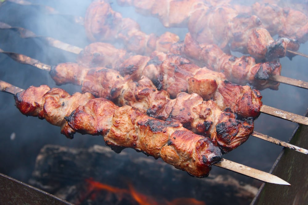 Things to Do In Puerto Rico.  Barbecue meat on skewers cooking outdoors closeup